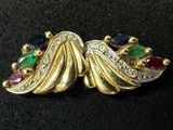 a close up of a gold brooch with multi colored stones
