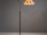 un lampadaire en laiton surmonté d'un abat-jour blanc