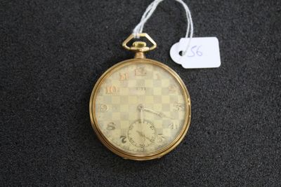 une montre de poche en or posée sur une surface noire, avec une étiquette de prix
