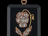 un gros plan d'un pendentif noir et doré orné d'une fleur