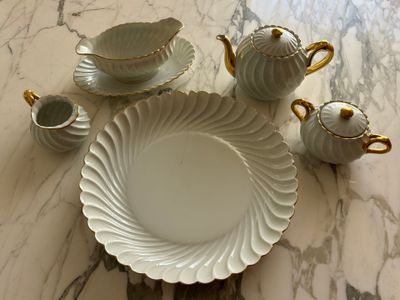 a table with a white plate and cups and saucers on it
