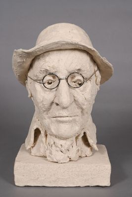 statue d'un homme portant des lunettes et un chapeau, posée sur une surface grise