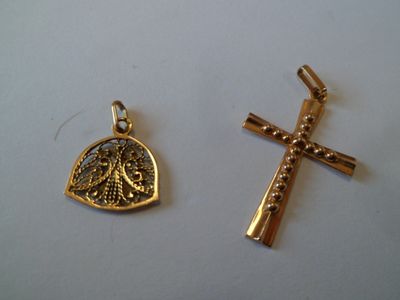 deux croix en or et un pendentif en forme de croix sur une surface blanche