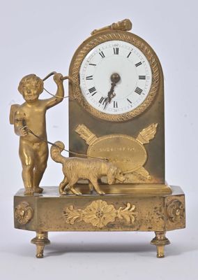 a gold clock with an angel and a dog on it