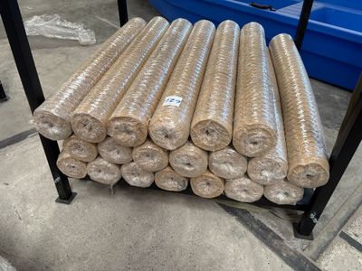 de nombreux rouleaux de tissu posés sur un support dans un entrepôt