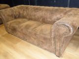 brown leather couch with studded arms in a living room setting