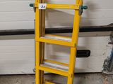 two yellow ladders sitting next to each other in front of a garage door