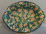 une assiette bleue ornée de fleurs, posée sur un socle
