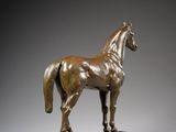 bronze statue of a horse on a wooden base on a gray background