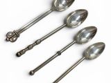 four silver spoons are lined up in a row on a white surface
