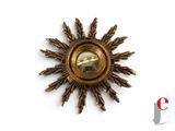 a gold sunburst with a mirror in the middle