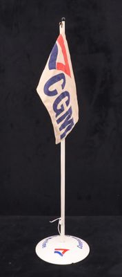 un petit drapeau posé sur un socle, sur une surface noire