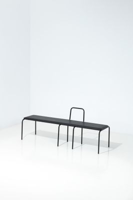 un banc noir et une chaise noire dans une pièce blanche