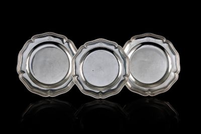 trois plats plaqués argent posés sur une surface noire