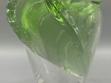 a glass vase with a green leaf decoration on it