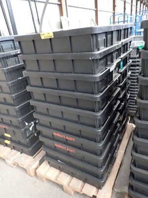 de nombreux conteneurs en plastique empilés sur une palette dans un entrepôt