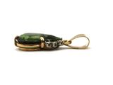 a close up of a green and gold pendant on a white background