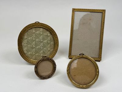 deux petits cadres dorés et un cadre photo posés sur une surface blanche