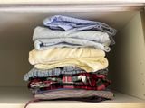 some folded shirts are stacked on a shelf in a closet