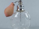 une petite bouteille en verre avec une poignée rose et un bouchon en métal