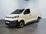 La camionnette blanche est garée dans une grande pièce équipée d'un ventilateur de plafond.