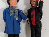 two dolls that are standing next to each other on a wall