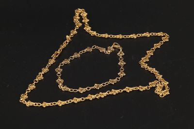 un gros plan d'un collier et d'un bracelet en or posés sur une surface noire