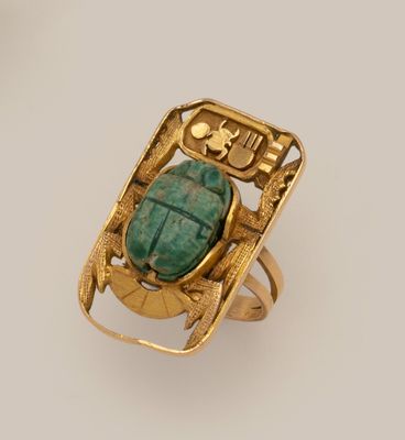 une image d'une bague en or avec une pierre verte au centre