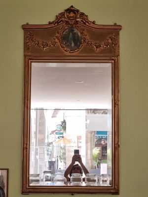 un miroir accroché au mur au-dessus d'une table sur laquelle se trouve un vase