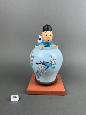 blue and white vase with a man sitting on top of it and a bird perched on top of the vase