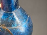 a hand holding a blue glass vase with a spider on it