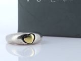 silver and gold heart ring in front of a box of jewelry