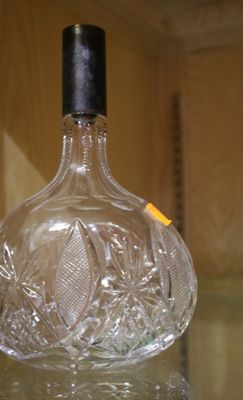 une bouteille en verre transparent avec un bouchon noir posée sur une table en verre