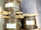 Plusieurs bobines de fil métallique sont empilées sur des palettes posées sur une surface métallique