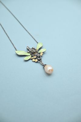 a close up of a necklace with a bee and a pearl