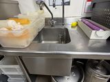 a sink in the middle of a kitchen with containers on the counter