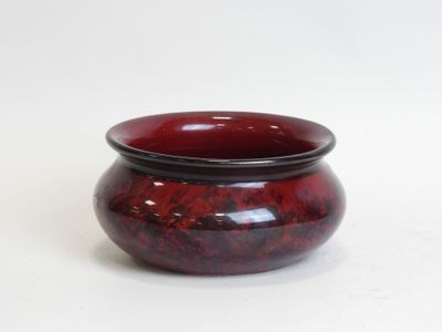 a red bowl with a black rim sitting on a white surface