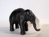 un petit éléphant noir debout sur une surface blanche