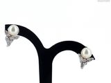 pair of pearl and diamond stud earrings on a black stand