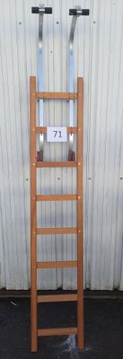 une échelle en bois appuyée contre un mur, sur laquelle est accrochée une pancarte