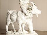 a statue of a child riding a goat on a table
