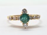 a close up of a gold ring with a green emerald and white diamonds