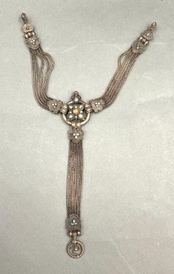 a close up of a necklace on a table with a white background