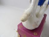 a figurine of a hand holding a book on top of a pink box
