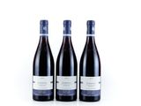three bottles of red wine sitting on top of a white surface