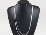 black mannequin with a silver chain on a black stand
