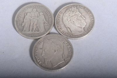 trois pièces d'argent posées l'une à côté de l'autre sur une surface blanche