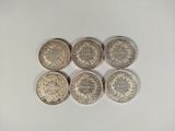 six different british coins sitting on top of a white surface