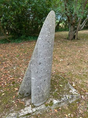 a stone sculpture in the middle of a field of leaves