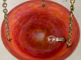 a red glass hanging from a chain with a light bulb in it